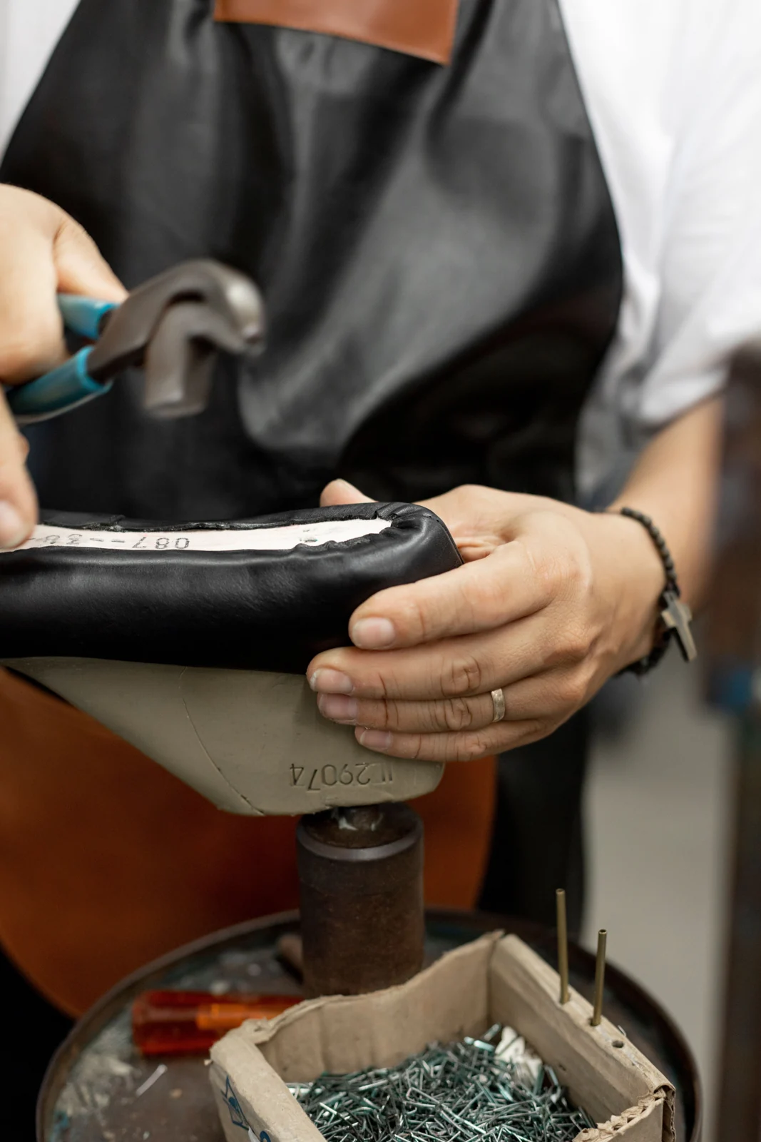A shoemaker working on a shoe mounted on a last